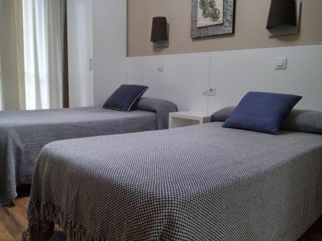 2 camas con almohadas azules en una habitación en Hostal Lesseps, en Barcelona
