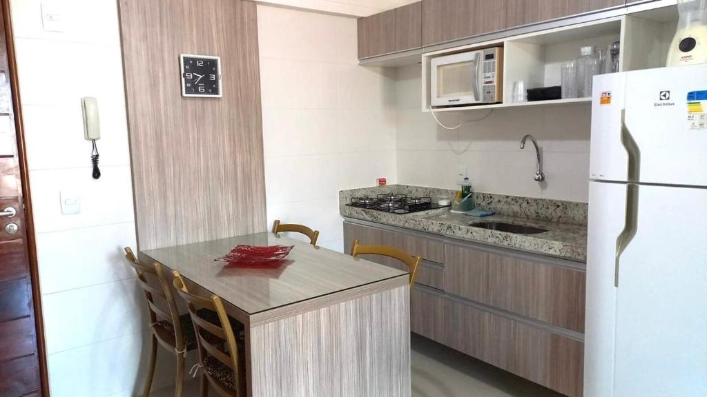 a small kitchen with a table and a refrigerator at Flat próximo ao mar, para até 4 pessoas in Cabedelo