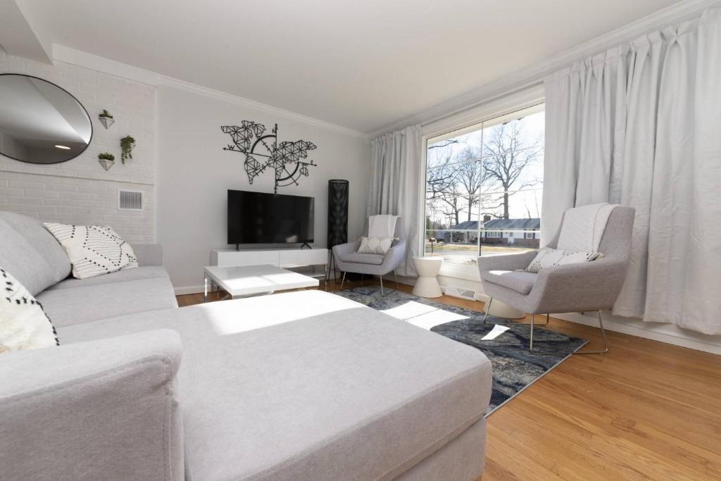 a white living room with a bed and two chairs at Admiral's Retreat - iTrip Annapolis in Annapolis