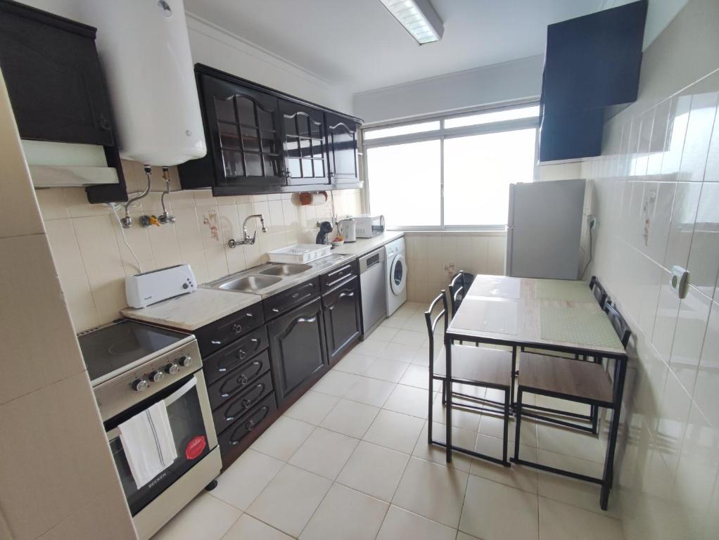 a kitchen with black cabinets and a table with chairs at Lisbon spacious T2 in Damaia, Lisbon in Amadora