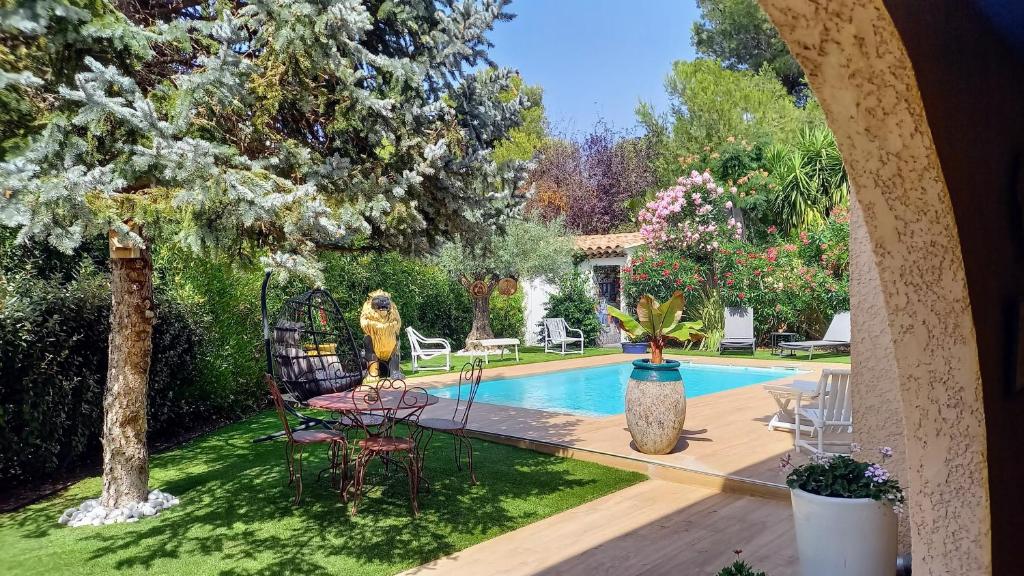 une cour arrière avec une piscine, une table et des chaises dans l'établissement Carry-le-Rouet, appartement 2 pièces, jardin et piscine, à Carry-le-Rouet