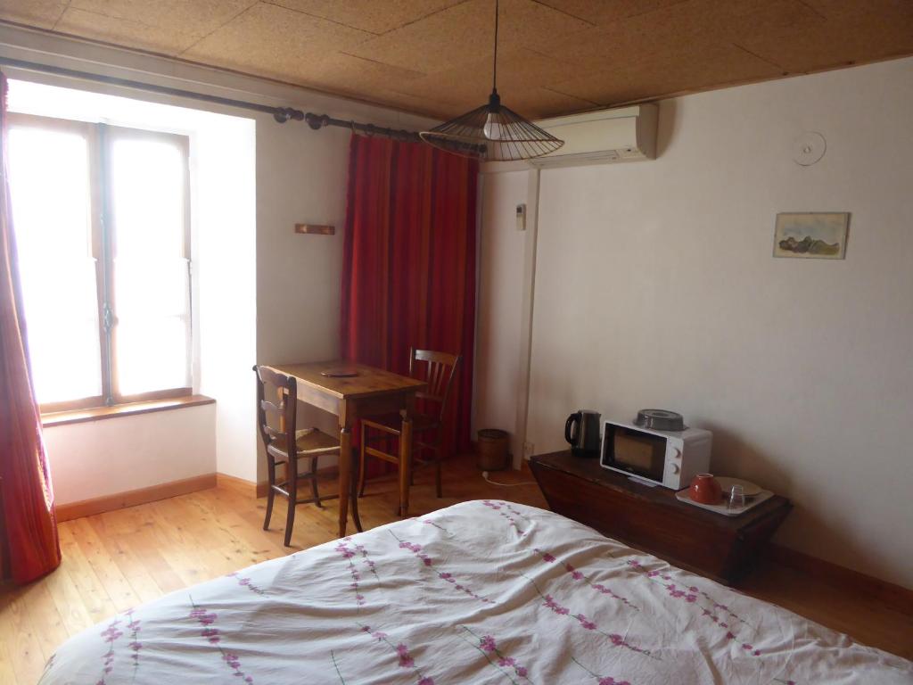 a bedroom with a bed and a desk with a microwave at chambre d'hôte calme au milieu d'un jardin au Freney d'oisans in Le Freney-dʼOisans