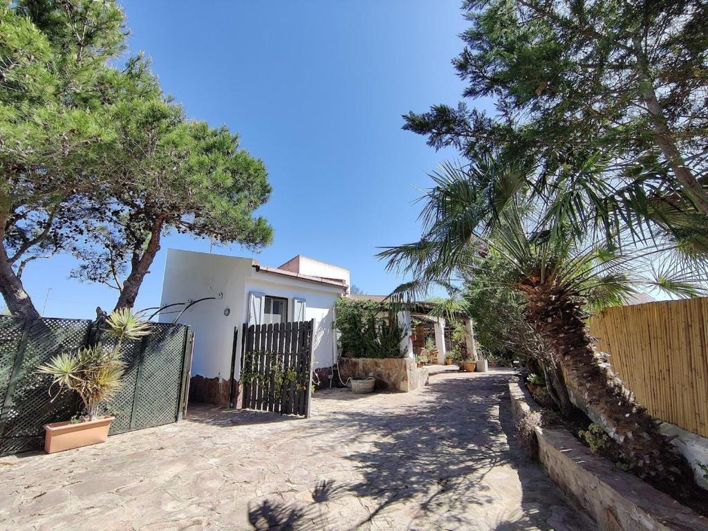 una casa bianca con alberi e una recinzione di VILLA with pool SU PREPPA 'S AUS a Carloforte