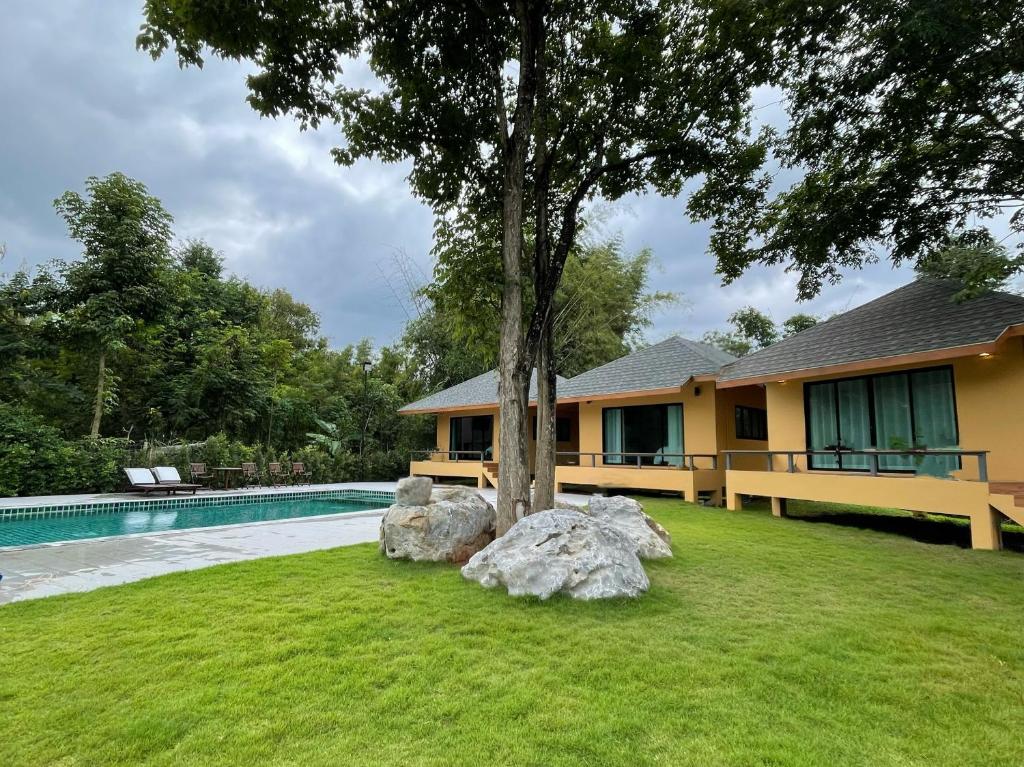 a house with a tree next to a swimming pool at Jindarin Villas จินดาริน คาเฟ่ in Ban Nong Sarai (1)