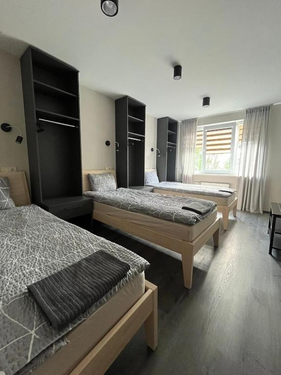a room with three beds and a window at Apartamenti Jēkabpilī in Jēkabpils