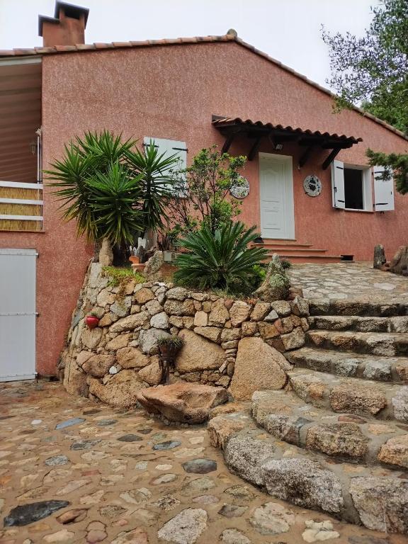 une maison en briques avec un mur et des escaliers en pierre. dans l'établissement Villa individuelle avec jardin, à Sartène