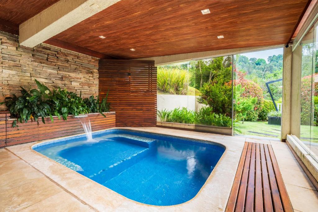 a swimming pool in a house with a patio at Pousada Grandchamp - Campos do Jordao in Campos do Jordão