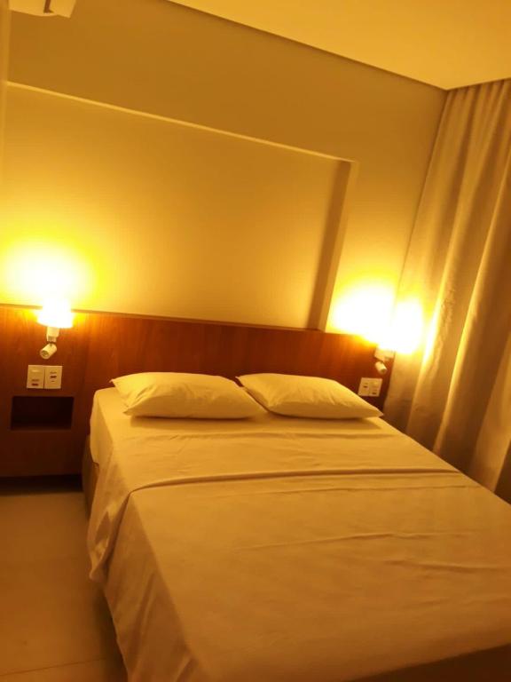 a bedroom with a white bed with two lights on it at Ap SALINAS EXCLUSIVE RESORT in Salinópolis