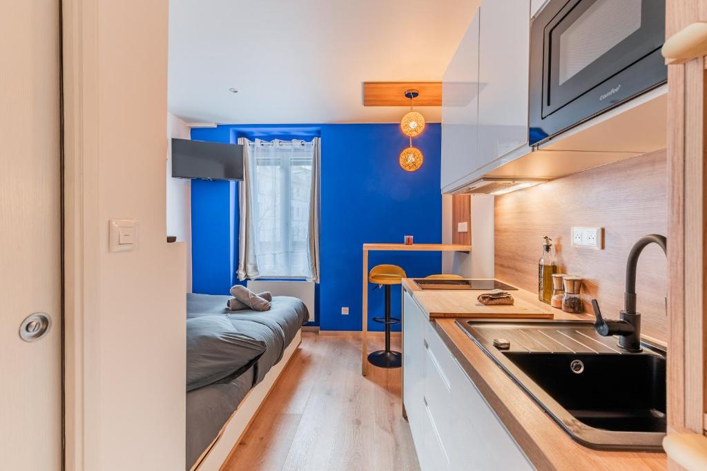 Elle comprend une petite cuisine avec des murs bleus et un évier. dans l'établissement Suite 1 - Strasbourg Gare - Petite France - Commerces à Proximité, à Strasbourg