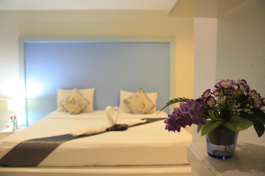 a bedroom with a bed with a vase of flowers at Phuket Racha Kata Homestay in Kata Beach