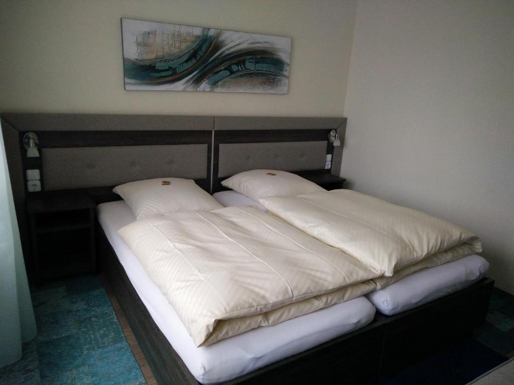 łóżko z 2 poduszkami w pokoju w obiekcie Hotel Alfa w mieście Neu-Isenburg