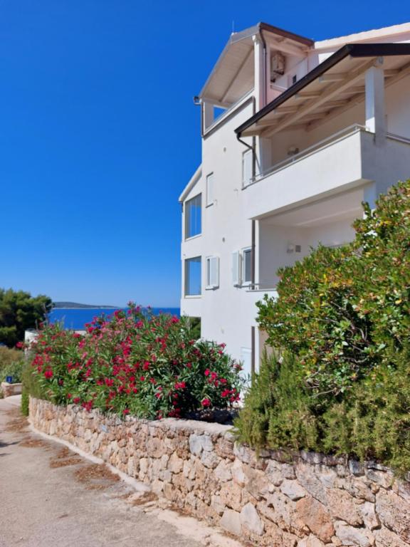 a white building with flowers and a stone wall at Sunny Terrace Zavala Hvar studio with terrace in Zavala