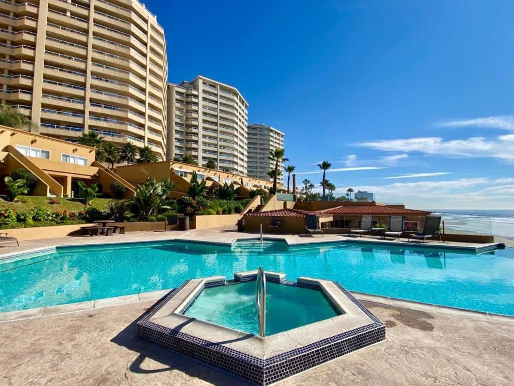 a large swimming pool in front of some buildings at Rosarito Beach and pool access apartment 2bd 2b in Popotla