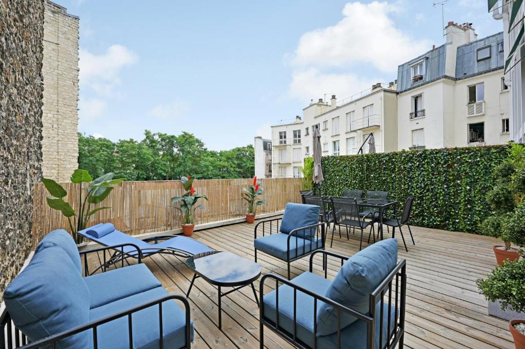 un patio avec des chaises et des tables sur une terrasse en bois dans l'établissement La Maison Bizot 41 T1 by ecoflats, à Paris