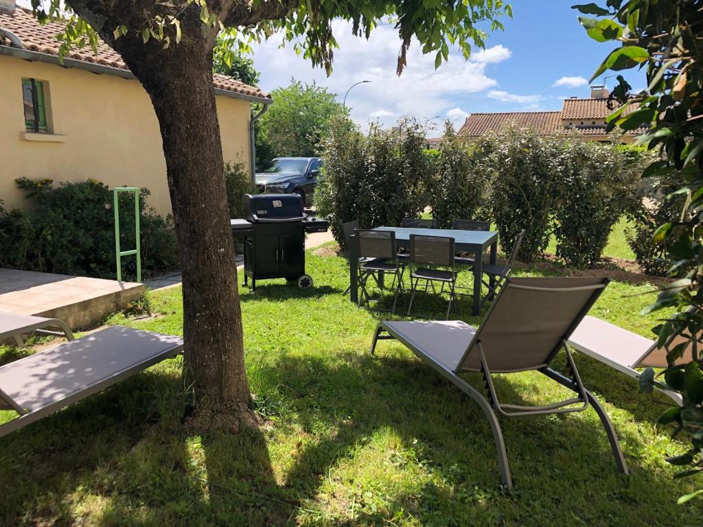 - une table de pique-nique et des chaises sous un arbre dans une cour dans l'établissement Gîte les Alouettes, à Uzès