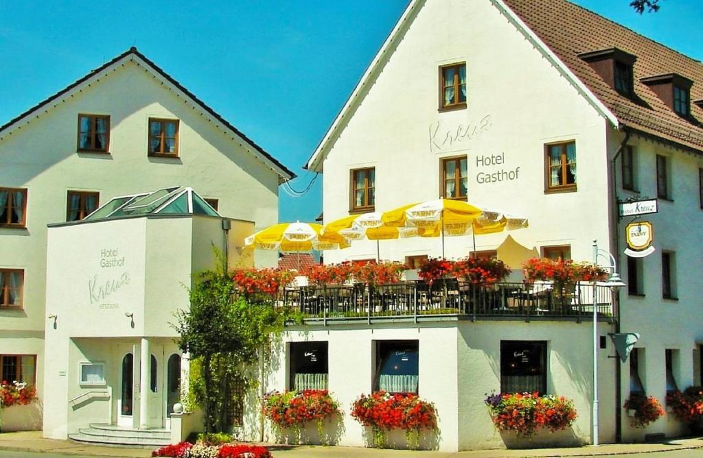 ein weißes Gebäude mit Sonnenschirmen und Blumen darauf in der Unterkunft Hotel Gasthof Kreuz in Bad Buchau