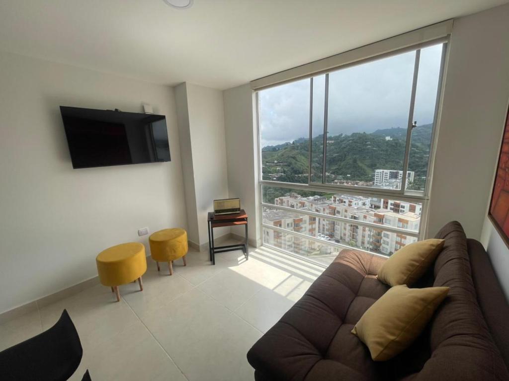 a living room with a couch and a large window at Muy Cerca al CC Fundadores, U Autonoma & El Centro in Manizales
