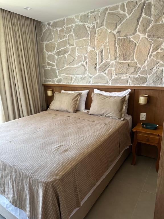 a bedroom with a large bed with a stone wall at Diamantino 08 Mucugê Luxo in Mucugê