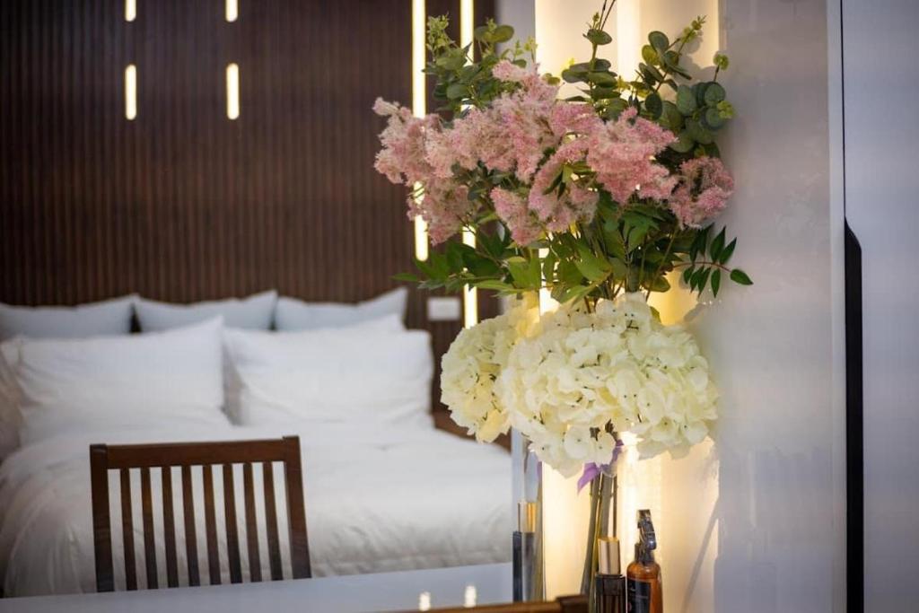 eine Vase mit Blumen auf einem Tisch neben einem Bett in der Unterkunft carpe diem staycation in Lapu Lapu City
