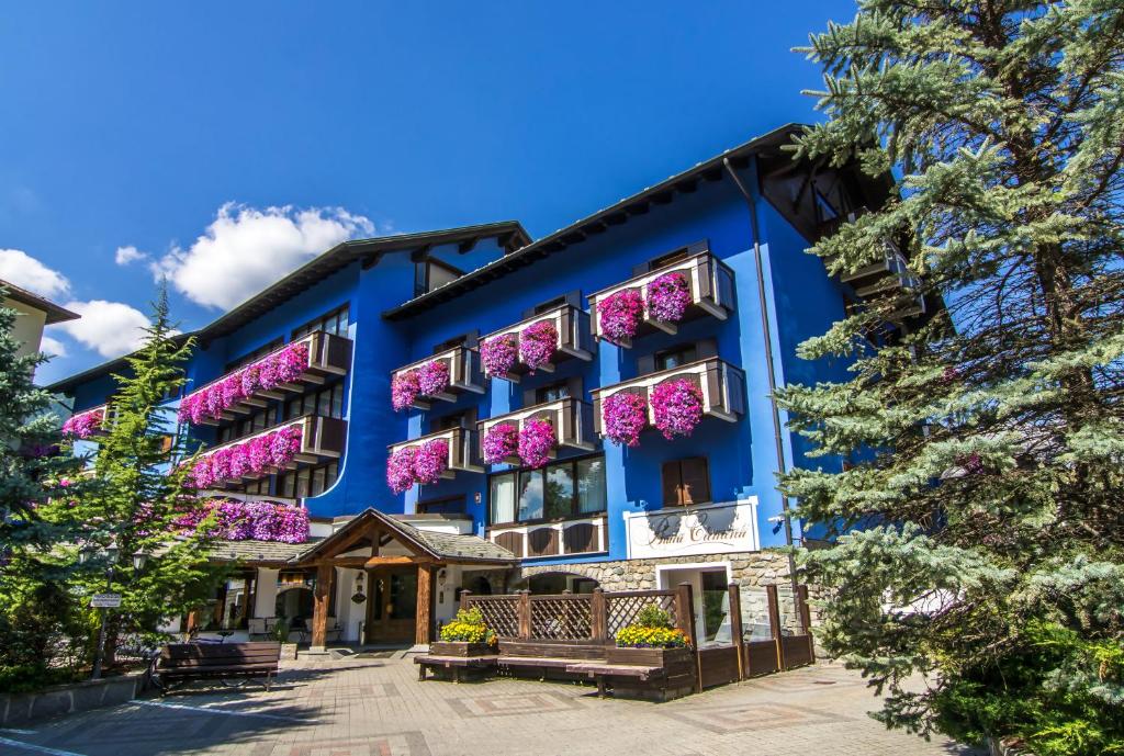 
a large blue building with a clock on the front of it at Hotel Baita Clementi in Bormio
