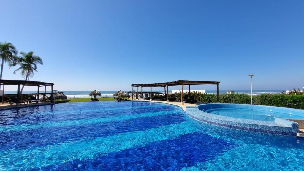 a large swimming pool with blue water in front of the ocean at Casa Acapulco Playa Bonfil in Acapulco