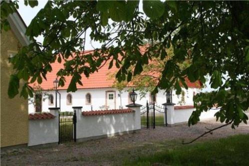 ein weißes Gebäude mit rotem Dach und einem Zaun in der Unterkunft Linda Gård in Yngsjö