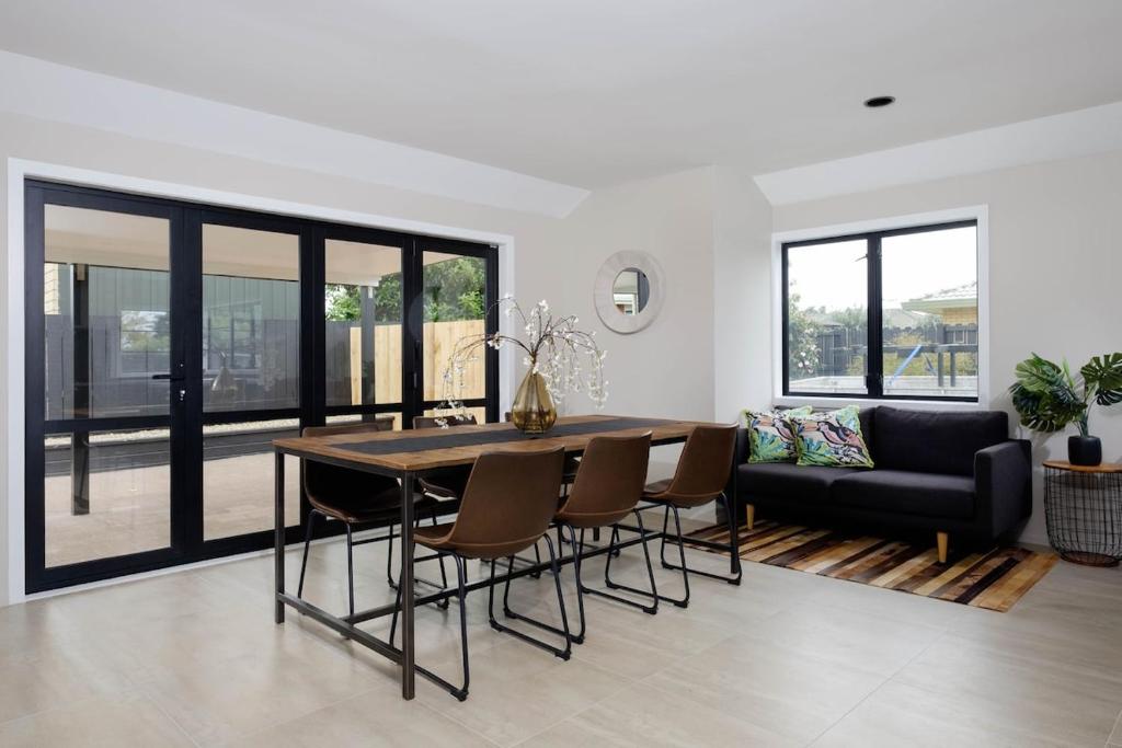 a dining room with a table and chairs and a couch at Mt Maunganui White House in Mount Maunganui