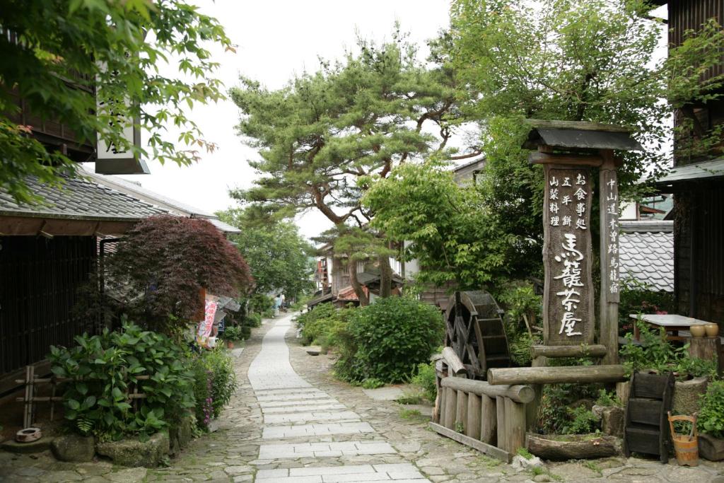 une rue dans un village asiatique avec un panneau et des arbres dans l'établissement Magome Chaya, à Nakatsugawa