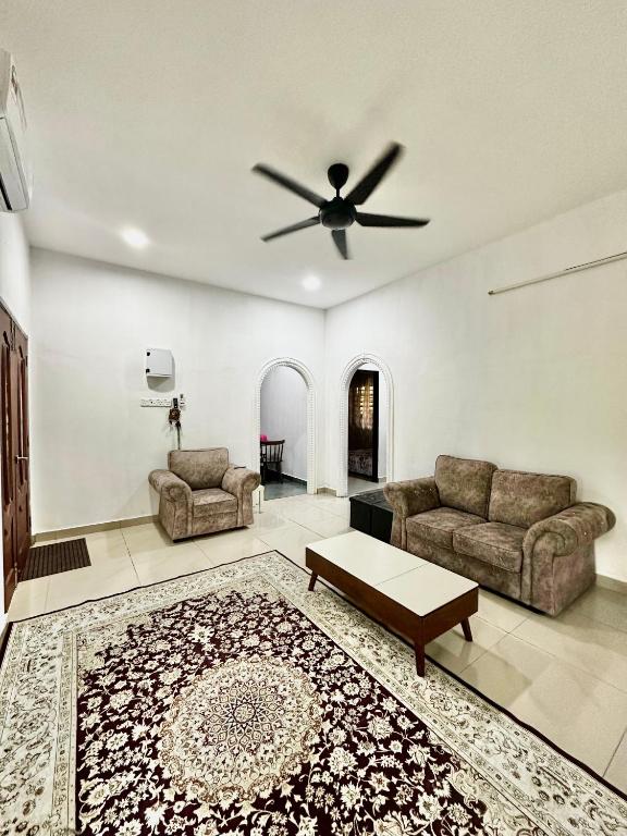 a living room with a couch and a ceiling fan at Rumah D Hutan in Kampong Cheh