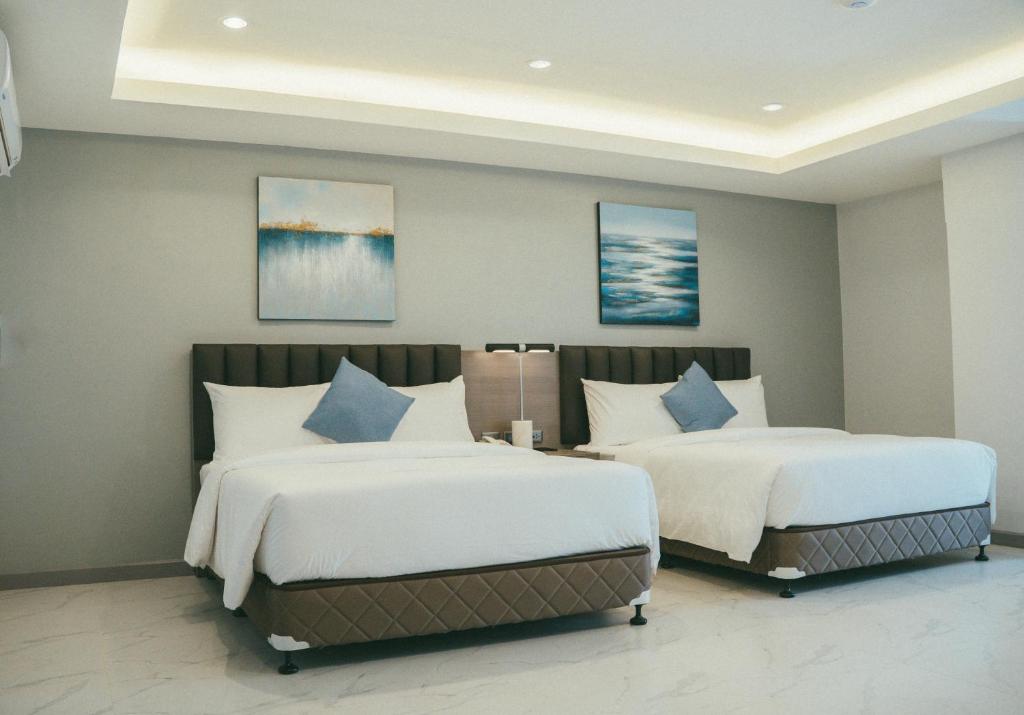 a bedroom with two beds with white and blue pillows at NS Royal Hotel in Cebu City