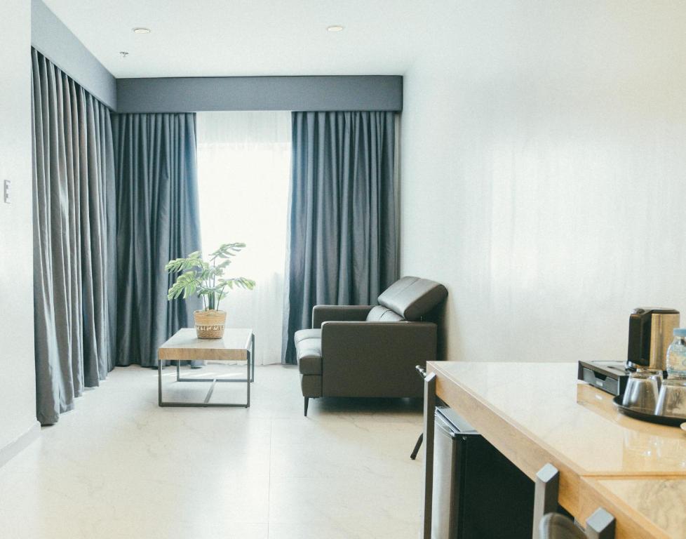 a living room with a couch and a chair in front of a window at NS Royal Hotel in Cebu City