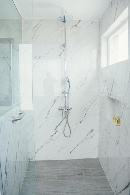 a bathroom with a shower with white marble walls at NS Royal Hotel in Cebu City