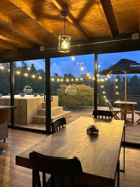 グアタペにあるGRETEL CHALETS SUIZOの大きな木製テーブル(椅子付)、大きな窓