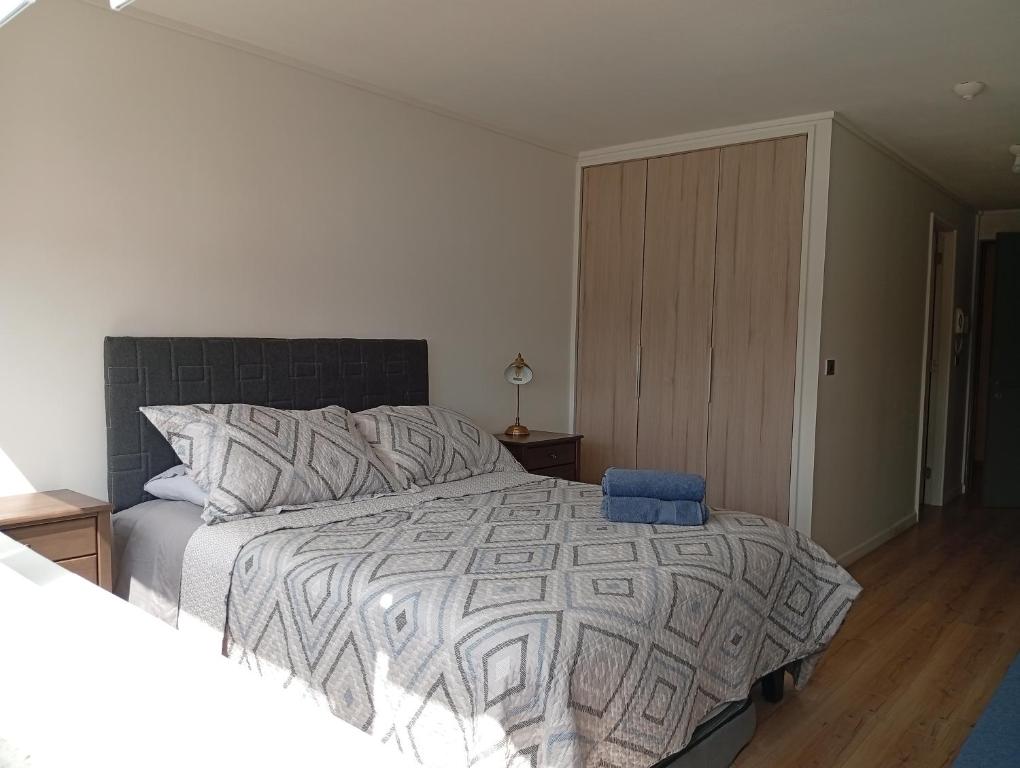 a bedroom with a large bed with a blue chair at Departamentos JM osorno in Osorno