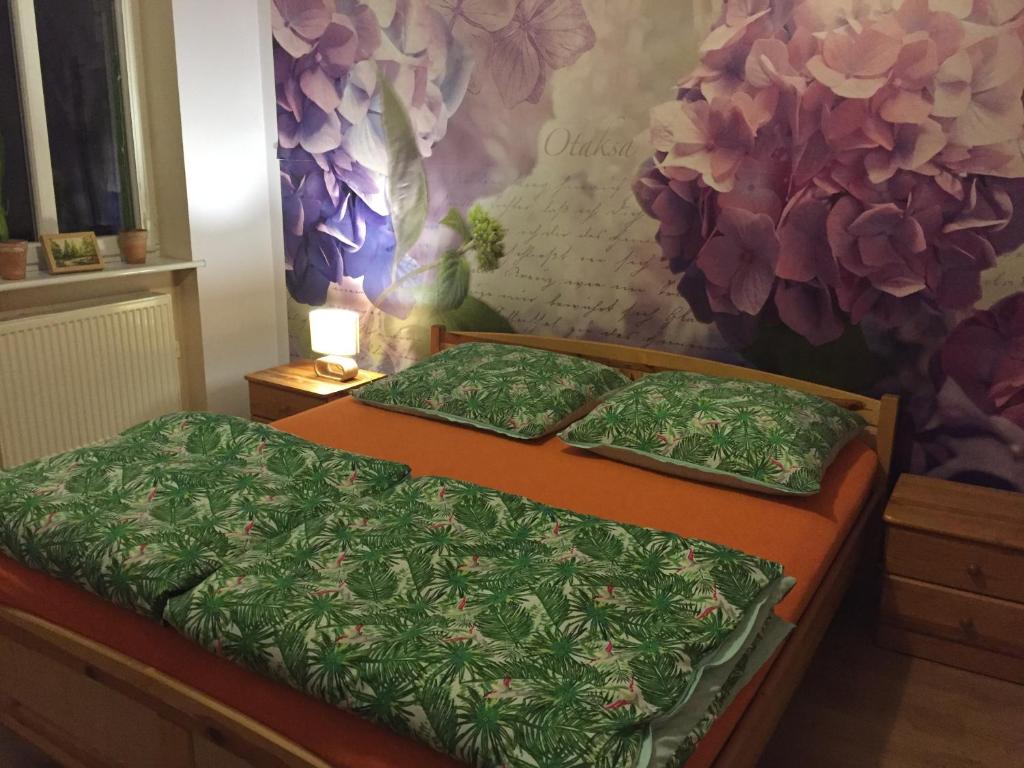 two twin beds in a room with a flower mural at Kawalerka Fredry 3/13 in Poznań