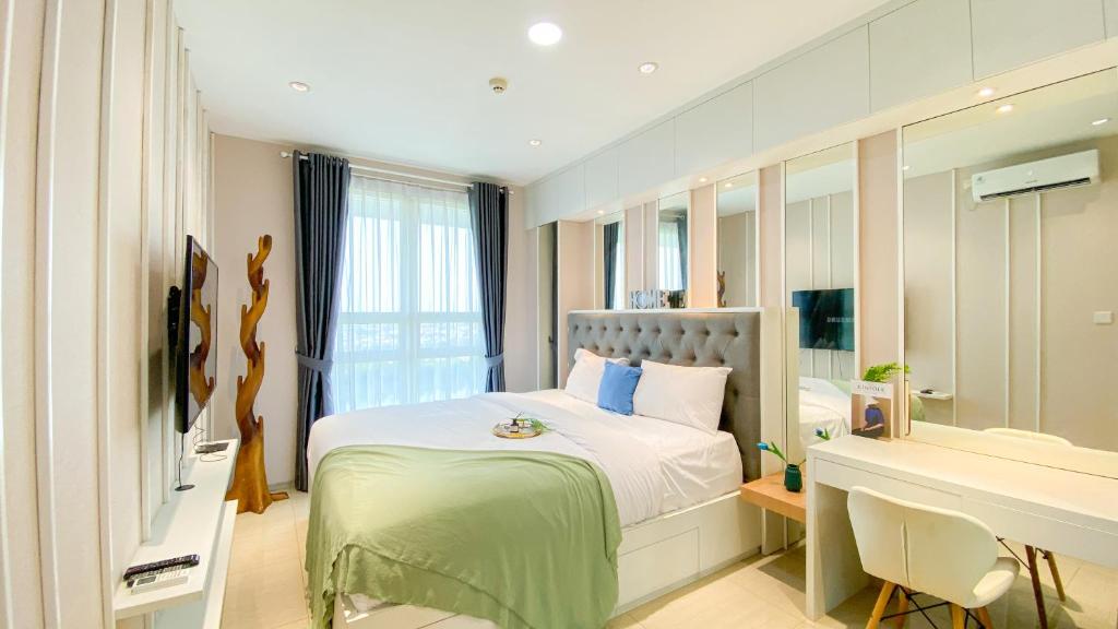 ein Schlafzimmer mit einem Bett, einem Schreibtisch und einem Waschbecken in der Unterkunft Fancy and Nice 1BR at Citralake Suites Apartment By Travelio in Jakarta