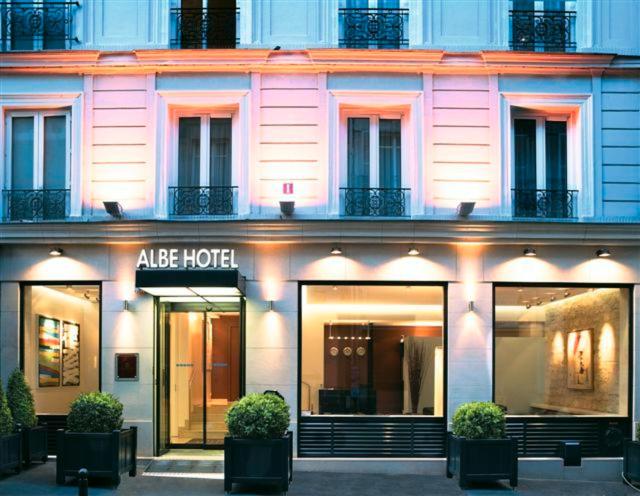 un bâtiment rose avec un hôtel aapo devant lui dans l'établissement Hôtel Albe Saint Michel, à Paris