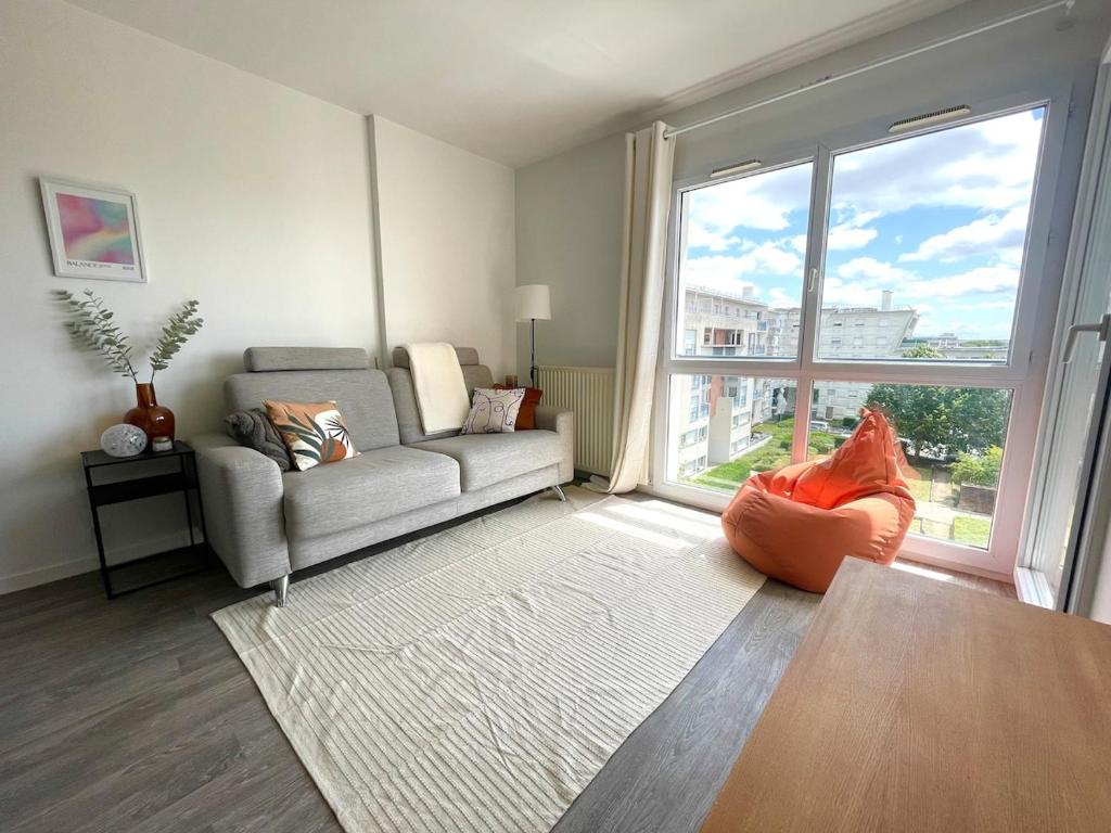 un salon avec un canapé et une grande fenêtre dans l'établissement 5 min Versailles & Golf National, à Guyancourt