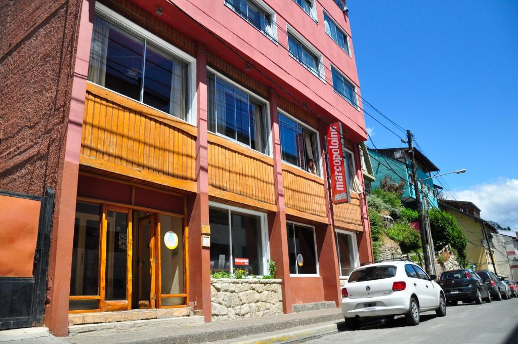 un coche blanco estacionado frente a un edificio en Marcopolo Inn Hostel Bariloche en San Carlos de Bariloche