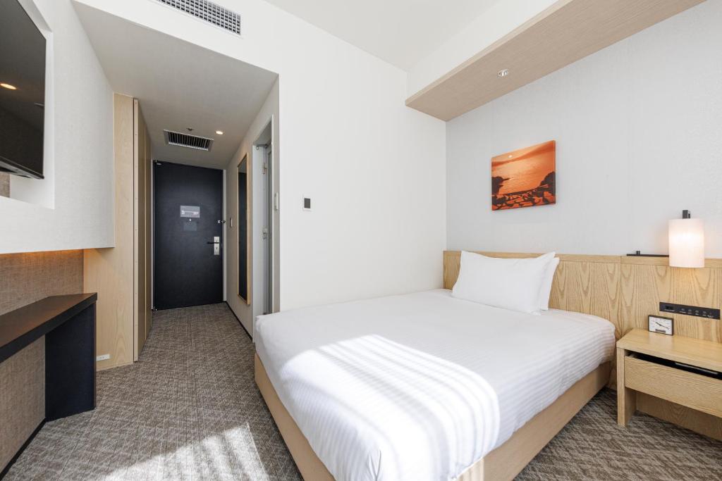 a hotel room with a bed and a television at JR Kyushu Hotel Blossom Shinjuku in Tokyo
