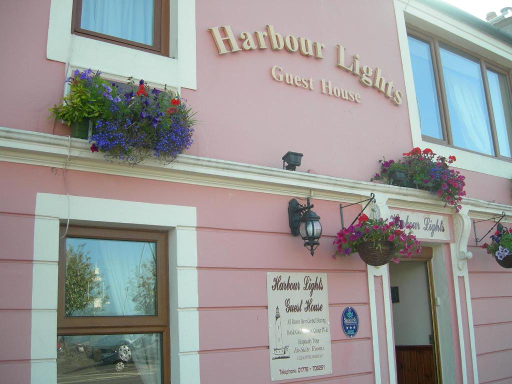 a pink building with flower pots on the front at Harbour Lights Guesthouse in Stranraer