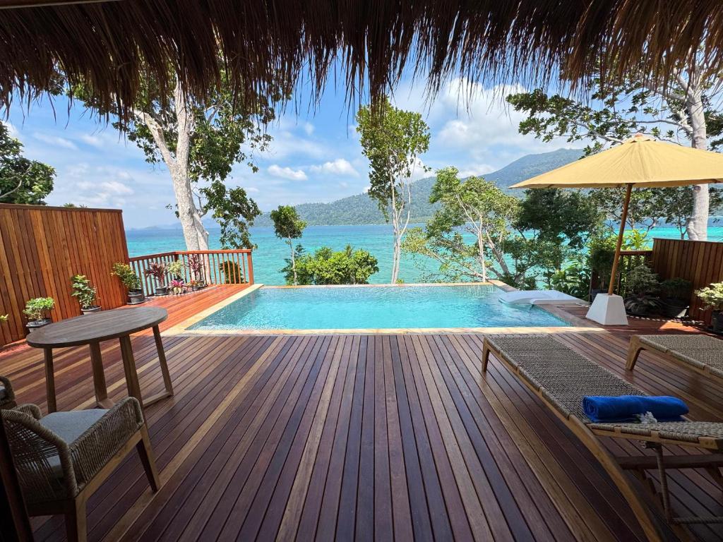 a swimming pool with a table and an umbrella on a deck at Ten Moons Sunset Villas in Ko Lipe