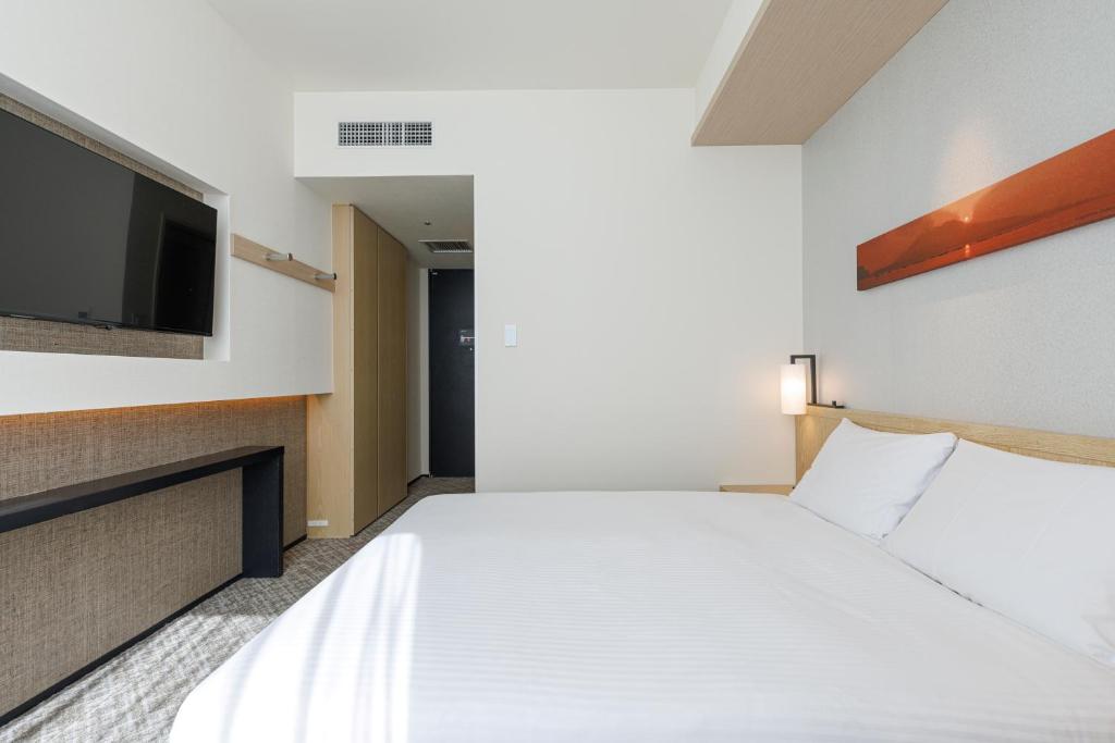 a hotel room with a bed and a flat screen tv at JR Kyushu Hotel Blossom Shinjuku in Tokyo