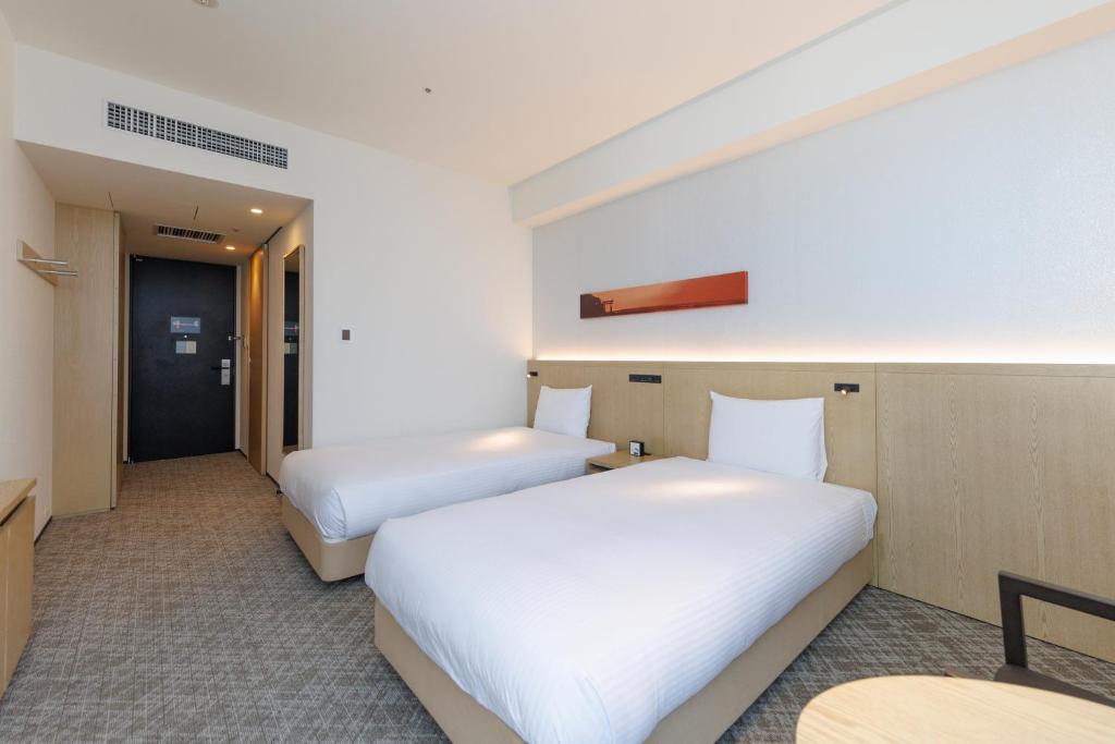 a hotel room with two beds and a table at JR Kyushu Hotel Blossom Shinjuku in Tokyo