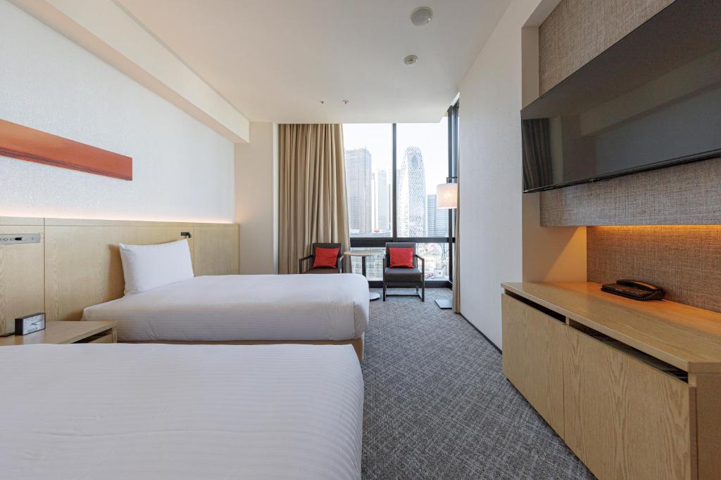 a hotel room with two beds and a television at JR Kyushu Hotel Blossom Shinjuku in Tokyo