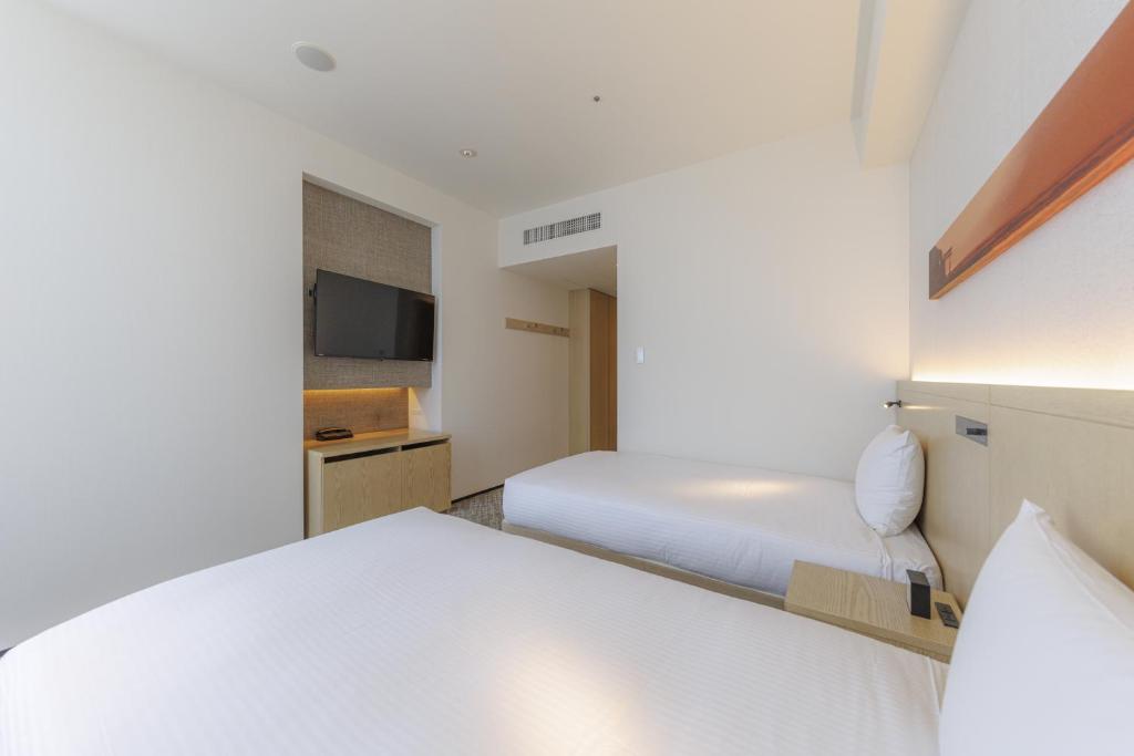 a hotel room with two beds and a tv at JR Kyushu Hotel Blossom Shinjuku in Tokyo