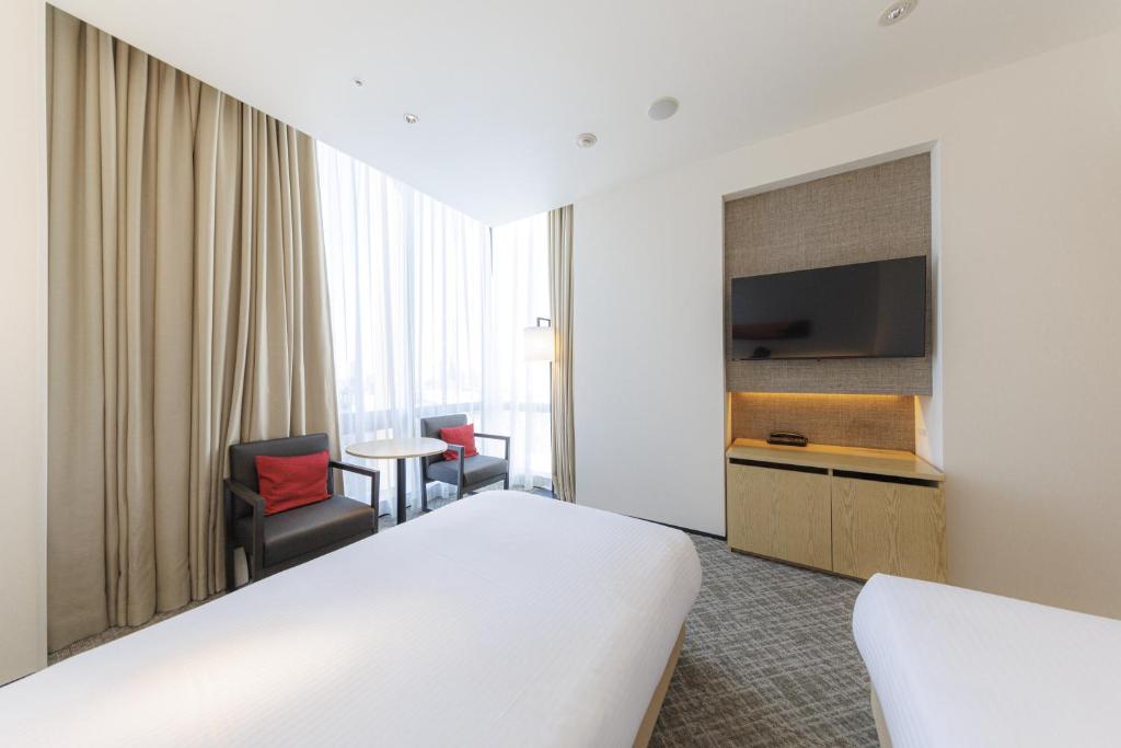 a hotel room with a bed and a flat screen tv at JR Kyushu Hotel Blossom Shinjuku in Tokyo