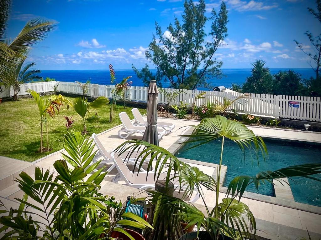 a swimming pool with chairs and the ocean in the background at La Caze Grande Anse in Petite Île