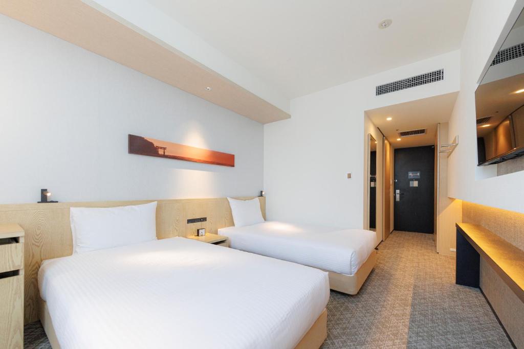 a hotel room with two beds and a tv at JR Kyushu Hotel Blossom Shinjuku in Tokyo