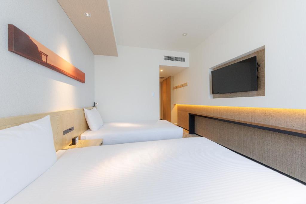 a hotel room with two beds and a tv at JR Kyushu Hotel Blossom Shinjuku in Tokyo
